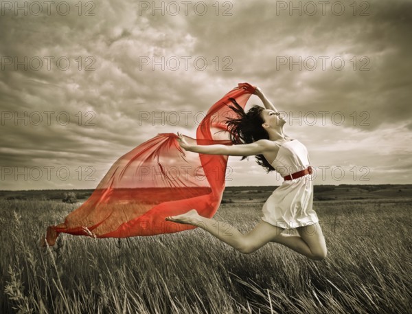 Brunette girl jumping with red fabric in summer day. Outdoors potrait