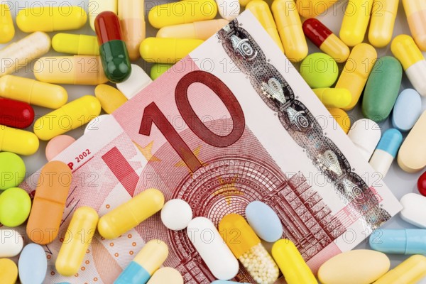 Euro banknotes and tablets, symbolic photo for costs of medication and health insurance. Austria