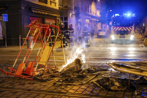 Bordeaux, France, April 17, 2023: Fire burning in the middle of a street of Bordeaux, France during a protest againt the retirement reform. French police in the background. High quality photography, Europe