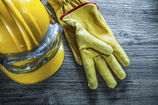 Safety gloves hard hat goggles on vintage wooden board
