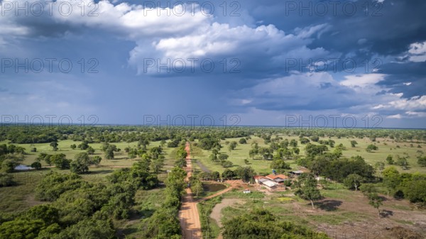 Aerial view of Transpantaneira dirt road with dramatic sky and rain crossing the typical landscape in North Pantanal Wetlands, Mato Grosso, Brazil, South America
