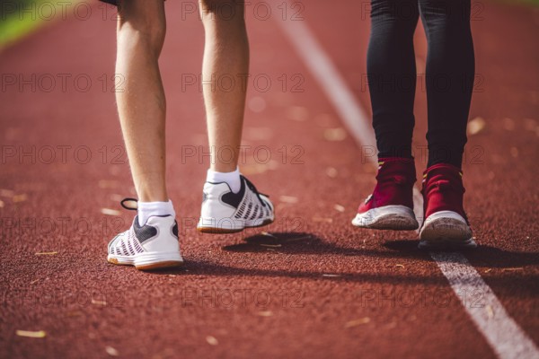 Subject is sport, physical development, sports training for school children in education. Close-up of legs of two children boy and girl running across red running stadium, back view