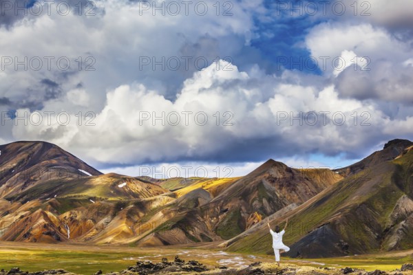 The elderly woman carries out pose of Tree in yoga among thermal sources. The picturesque valley in Landmannalaugar national park