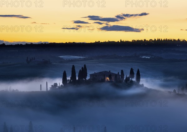 Tuscany farmhouse in morning mist with yellow skies, Val d'Orcia, Italy, Europe