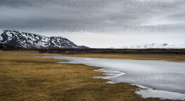 Typical Icelandic dramatic landscape with frozen lake and mountains covered in snow in Iceland
