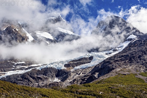 Impressive snow-covered peaks under a clear sky, framed by dramatic clouds, the glaciers of the Torres del Paine National Park in Patagonia, Chile, South America