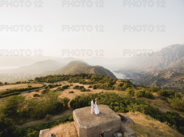The bride and groom hold hands on the roof of the Gorazda fort, behind them a view of the Bay of Kotor. High quality 4k footage