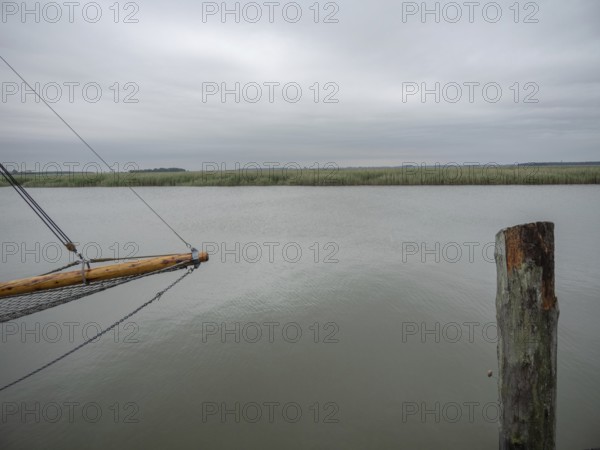 Wooden jetty and a single post jutting out into a vast, calm lake, zingst, baltic sea, germany