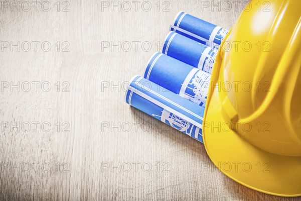 Wooden board with blue rolled construction drawings safety helmet