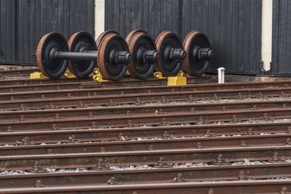 Several railway wheels are lined up next to each other on the rails in front of a building, bochum, westphalia, germany