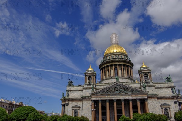 Building with golden dome under blue sky with clouds and trees in the foreground, saint petersburg, baltic sea, russia