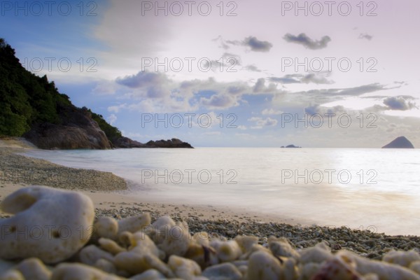 Peaceful and tropical coral turtle beach at Perhentian Islands, Malaysia, long exposure, with cloudy sky during sunset. Postcard, mural or wallpaper about Malaysian tourism or travel, Asia