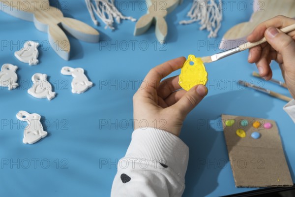 Master class of coloring Creator is using white air dry clay for making decor to EASTER holiday. Creating hobby recreation activity that involves fingers. DIY crafting Modern art