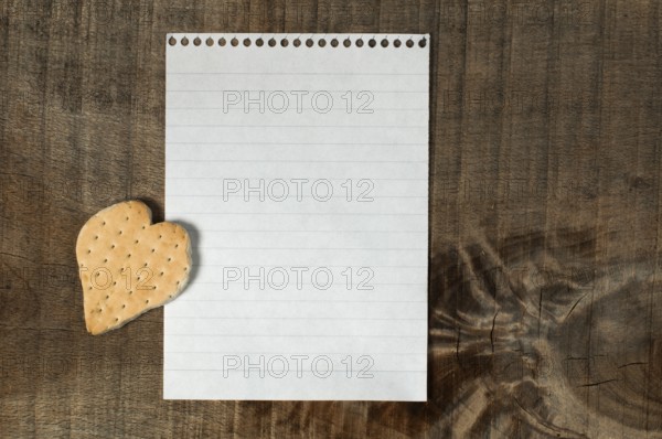 Heart shape cookie on wooden background and white paper sheet