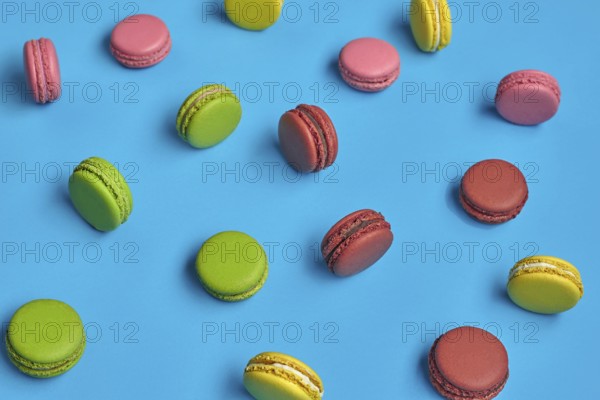Top view of a nice macarons or macaroons, sweet meringue-based confection with a ganache, buttercream or jam filling sandwiched between two such cookies. Tasty biscuits on blue background. Close-up, copy space