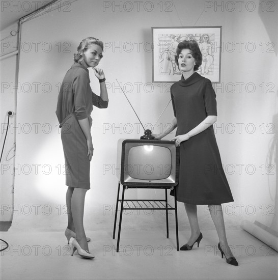 Television in the 1950s. Two young women are standing dressed in a typical 50s dress beside a televison set with an table antenna on top of it. In 1952 1.4 million households in Britain had a television. Photo Kristoffersson ref BZ26. Sweden 1952