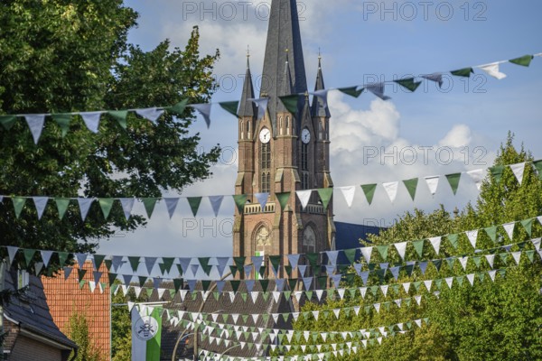 Church with high tower and flags, surrounded by trees, borken, münsterland, germany