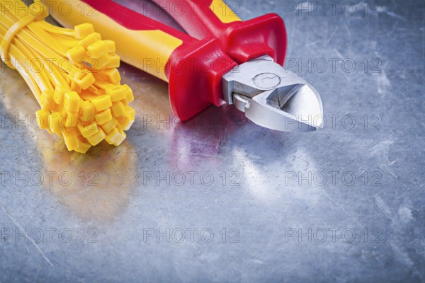 Wire-cutter cable ties on metallic background construction concept