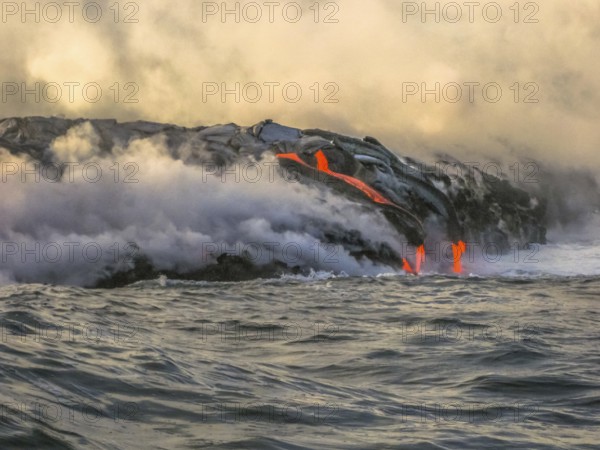 Volcanic activity with smoke and steam given off by lava contact with Pacific Ocean. Kilauea Volcano in Hawaii Volcanoes National Park, Big Island. Sea view of lava rivers into the sea