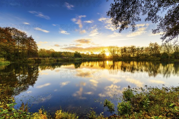 Beautiful sunrise at the lake with reflection in the water and clouds moving