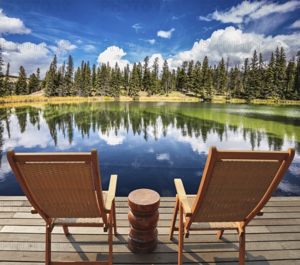 Two wooden deckchairs for tourists on ashore shallow round lake. Autumn day in Jasper National Park in the Rocky Mountains of Canada