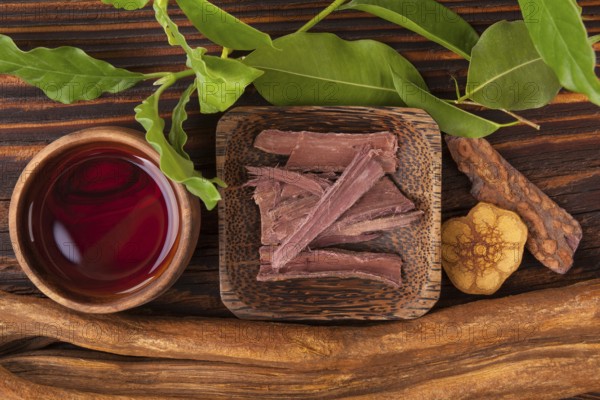 Ayahuasca brew in bowl with ingredients on wooden table from above. Banisteriopsis caapi, mimosa hostilis, psychotria viridis