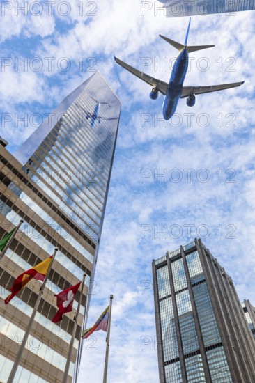 Plane reflecting on modern glass building facade while flying through the sky, Hong Kong island. Concept of transport, travel and business. Urban Central district cityscape