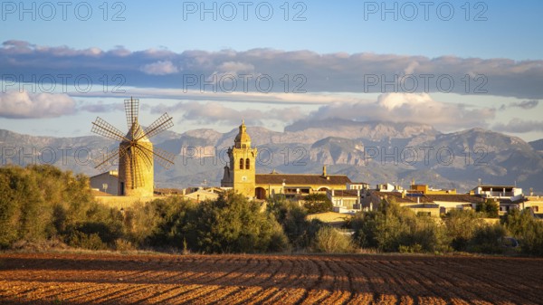 Cosy village with windmill and church and mountains in the background under a cloudy sky, Algaida, Majorca, Spain, Europe