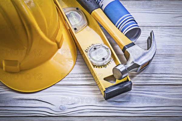 Claw hammer building helmet blue rolled engineering drawings construction level on wooden board