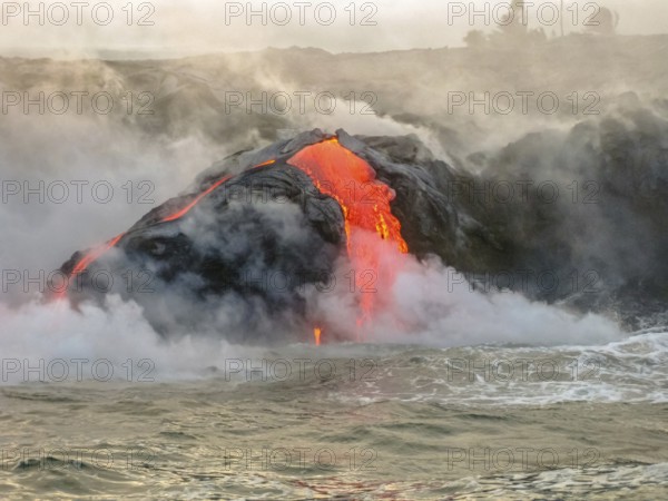 Sea view of Kilauea Volcano in Big Island, Hawaii, United States. Shot taken at sunset when the lava glows in the dark as jumps into the sea. The Kilauea erupting since 1983