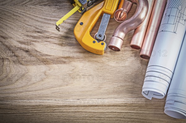 Blueprints tape measure water pipe cutter fittings on wooden board plumbing concept