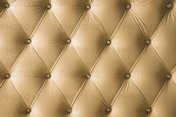 Beige soft textile background with symmetrical buttons on the corners of diamonds. Soft and expensive furniture elements. Luxury background