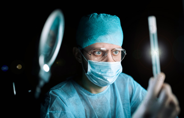A focused medical professional in a lab examining a sample with a magnifying tool