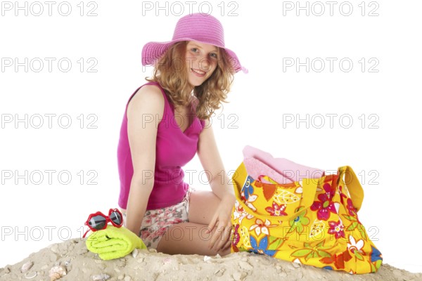 Woman sitting at the beach with pink hat in studio isolated over white background
