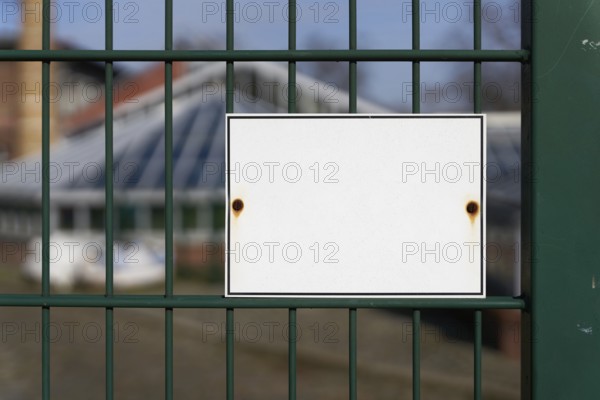 Unlabelled white sign on a fence with space for text