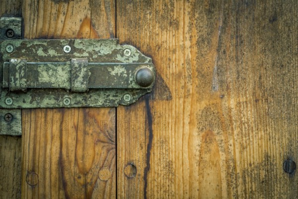 Wooden door from a german stable, with its rusty metal latch and aged wooden planks. Good frame with copy space on the right side for your text