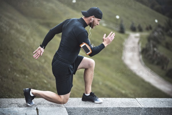 Young caucasian male jogger with fitness tracker attached to arm do warming up before jogging
