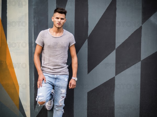 Handsome blue eyed young man standing against colorful wall, wearing t-shirt