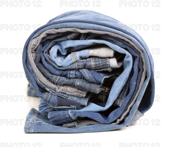 Different jeans rolled up on a white background