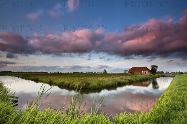 Farmhouse and river at dramatic pink sunset, Netherlands