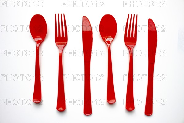 Single use red plastic cutlery on a white background. Concept: Ban single use plastic