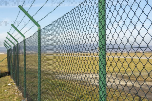 Green steel wire mesh fence around the airport area. Restricted area protection