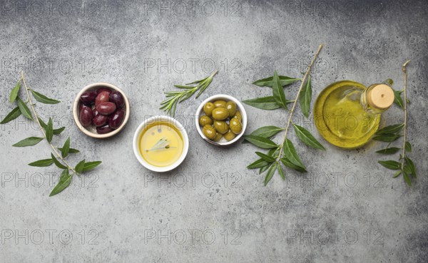 Composition with green and brown olives, extra virgin olive oil in glass bottle, olive tree branches on gray concrete stone rustic background overhead, Mediterranean concept, food photography, food photography