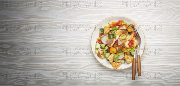 Traditional Levant dish Fattoush salad, Arab cuisine, with pita bread croutons, vegetables, herbs. Healthy Middle Eastern vegetarian salad, rustic wooden white background top view, food photography, food photography