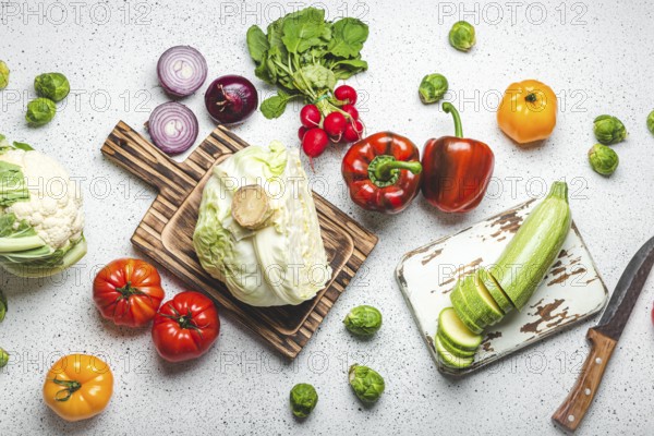 Fresh various vegetables with wooden cutting boards and knife on white kitchen table top view. Cooking vegetarian meal from healthy ingredients, diet food and nutrition concept, food photography, food photography