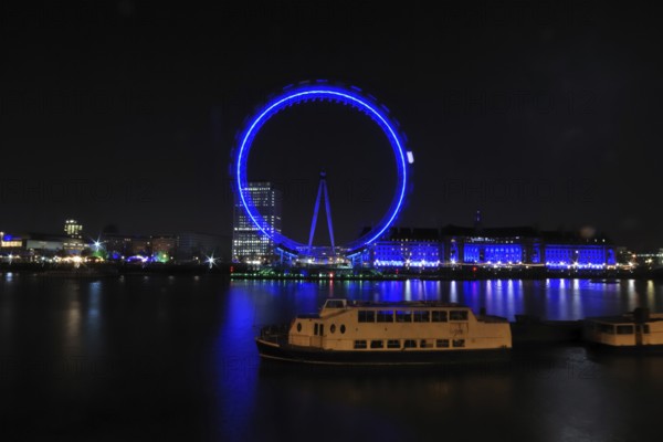 London Eye at night from the north bank with a ship in the foreground