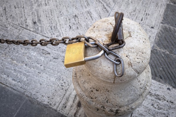 An image of a chain with a lock on a stone pillar