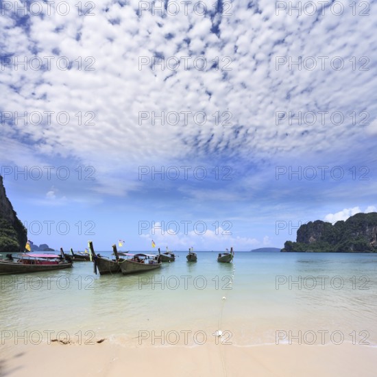 Light cirrus clouds over the warm sea. Picturesque native boat Longtail waiting on the beach the first tourists