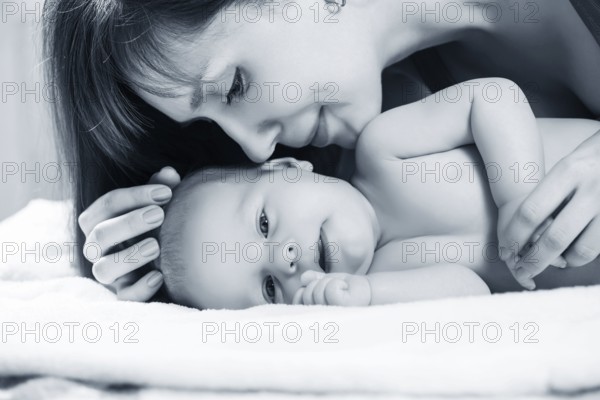 Closeup portrait of cheerful young mother with adorable newborn baby having fun at home, child care, happy parenthood, love concept