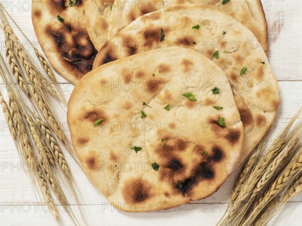 Fresh naan bread on white wooden background with copy space. Top view of several perfect naan flatbreads on metal tray